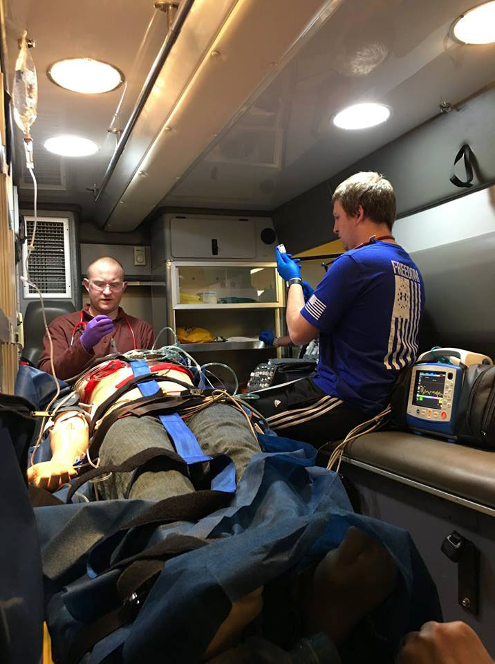 Paramedic students in back of ambulance with patient