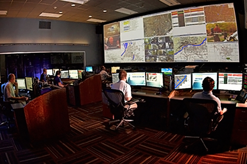 dispatch communication room showing computer desks and large video screens